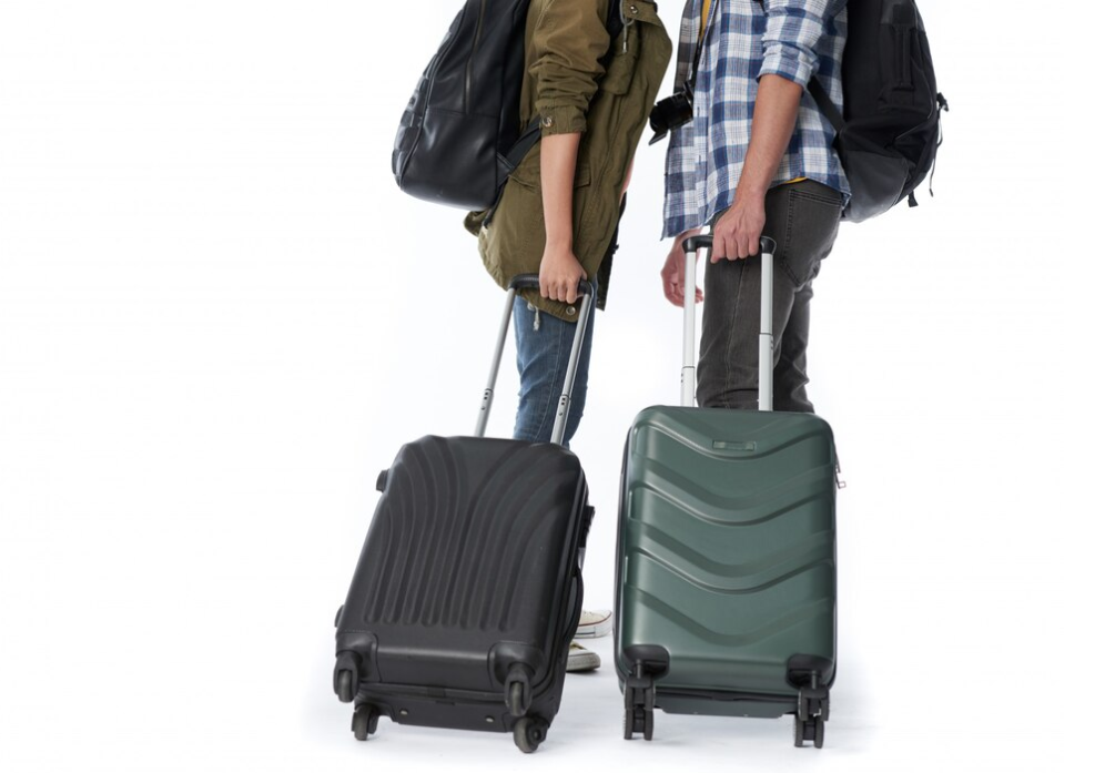 Two individuals with backpacks standing side by side, each pulling a suitcase